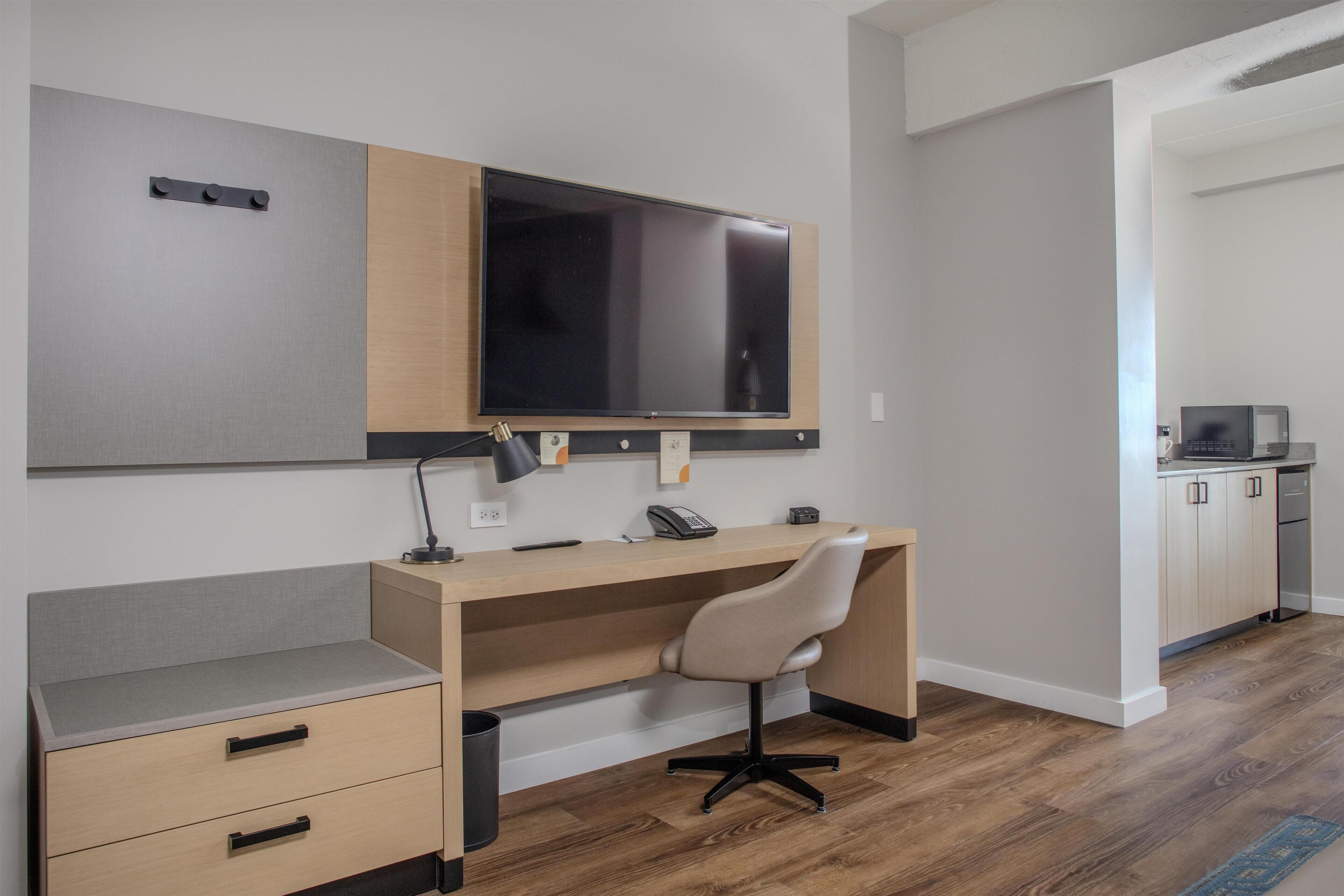 A modern office space with a desk, chair, and a mounted flat-screen TV.