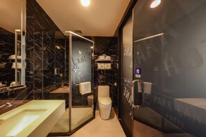 Een moderne badkamer met een douchecabine van glas, een betegelde muur van marmer en een grote spiegel.