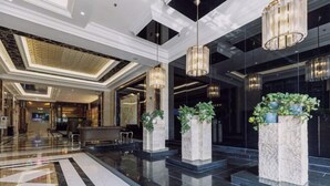 Eine moderne Lobby mit poliertem Marmorboden, großen Säulen mit Bepflanzung und zeitgemäßen Leuchten.