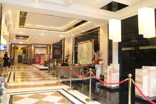 Un vestíbulo de hotel con piso a cuadros, una recepción y una barrera de cuerda roja.