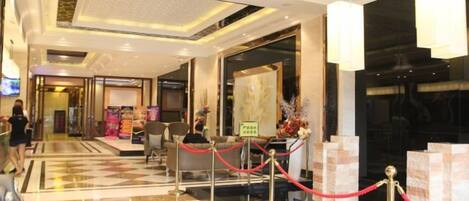 Un vestíbulo de hotel con piso a cuadros, una recepción y una barrera de cuerda roja.