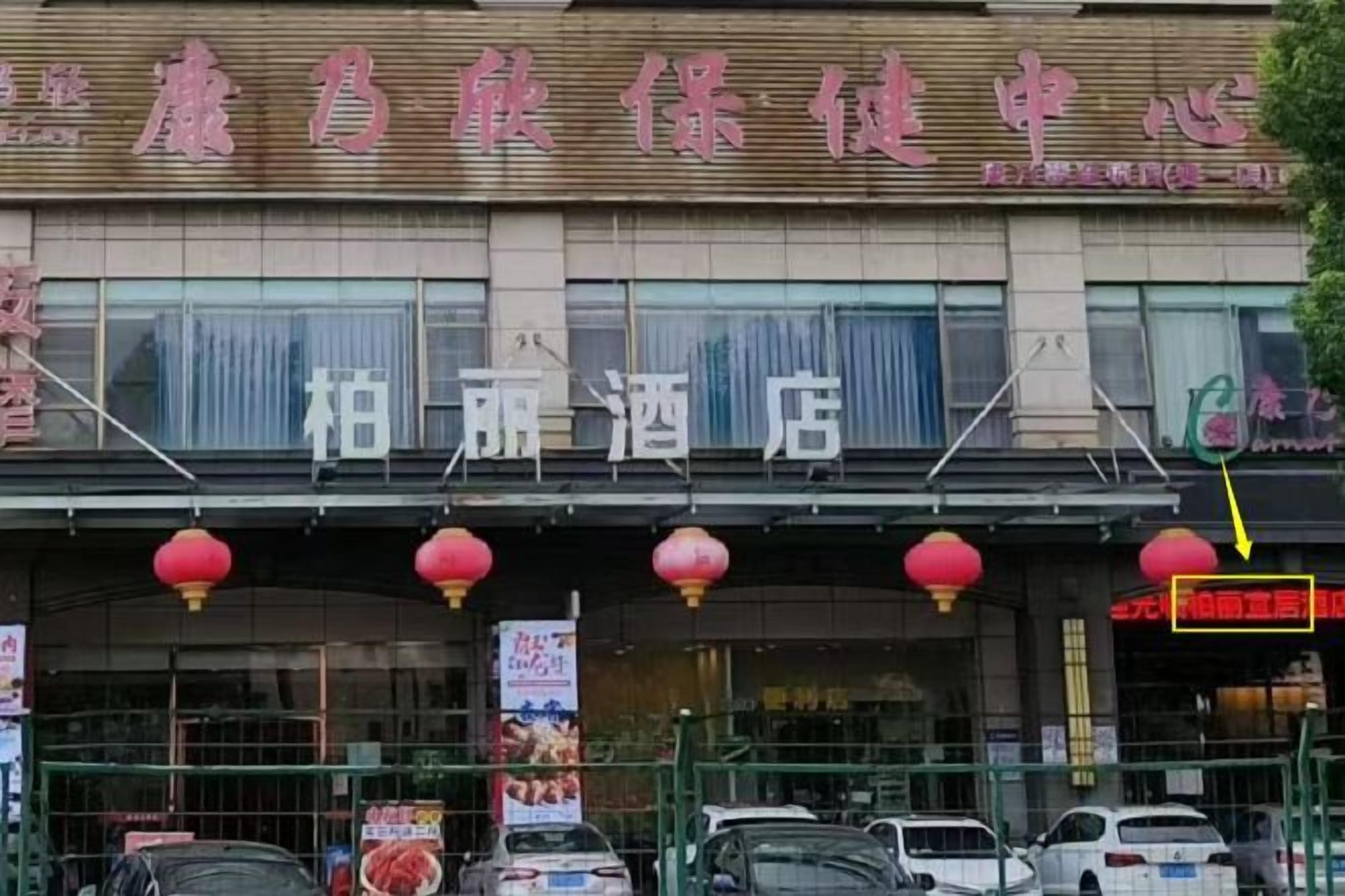 A hotel with a signboard, multiple windows, and a red lantern decoration.