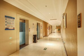 Un couloir d’hôtel avec des portes, une poubelle et un panneau sur le mur.