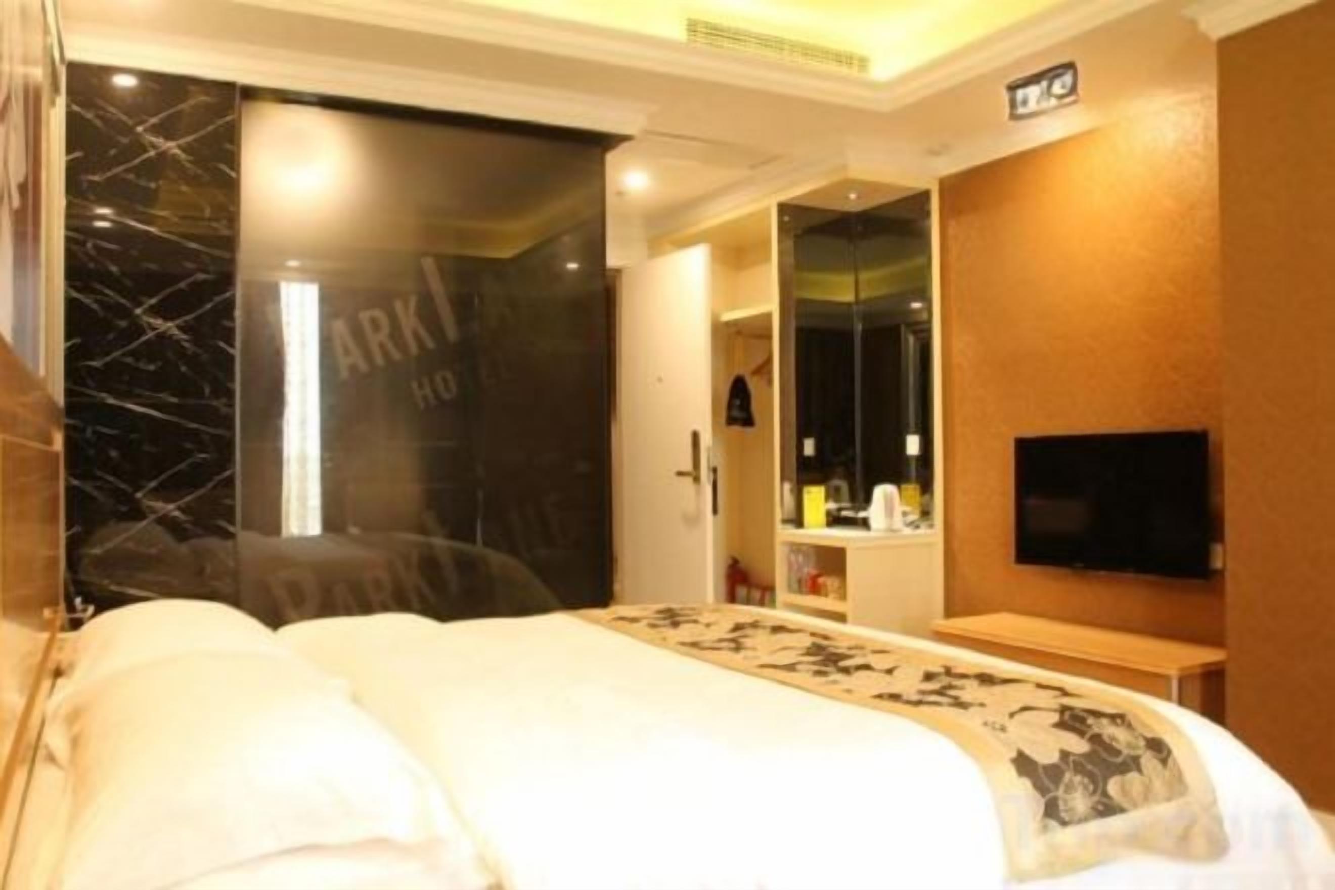 A hotel room with a bed, a television, a mirror, and a wardrobe.