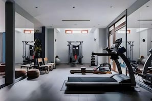 Ein modernes Fitnessstudio mit Trainingsgeräten, einem Laufband und einer Spiegelwand.