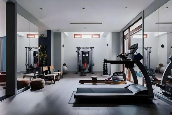 A modern gym with exercise equipment, a treadmill, and a mirrored wall.