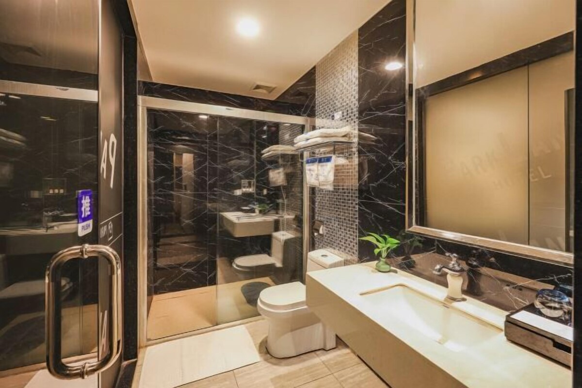 Een moderne badkamer met een douchecabine van glas, een wit toilet, een wastafel met spiegel en een klein plantje op het aanrecht.