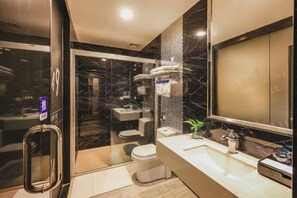 Een moderne badkamer met een douchecabine van glas, een wit toilet, een wastafel met spiegel en een klein plantje op het aanrecht.