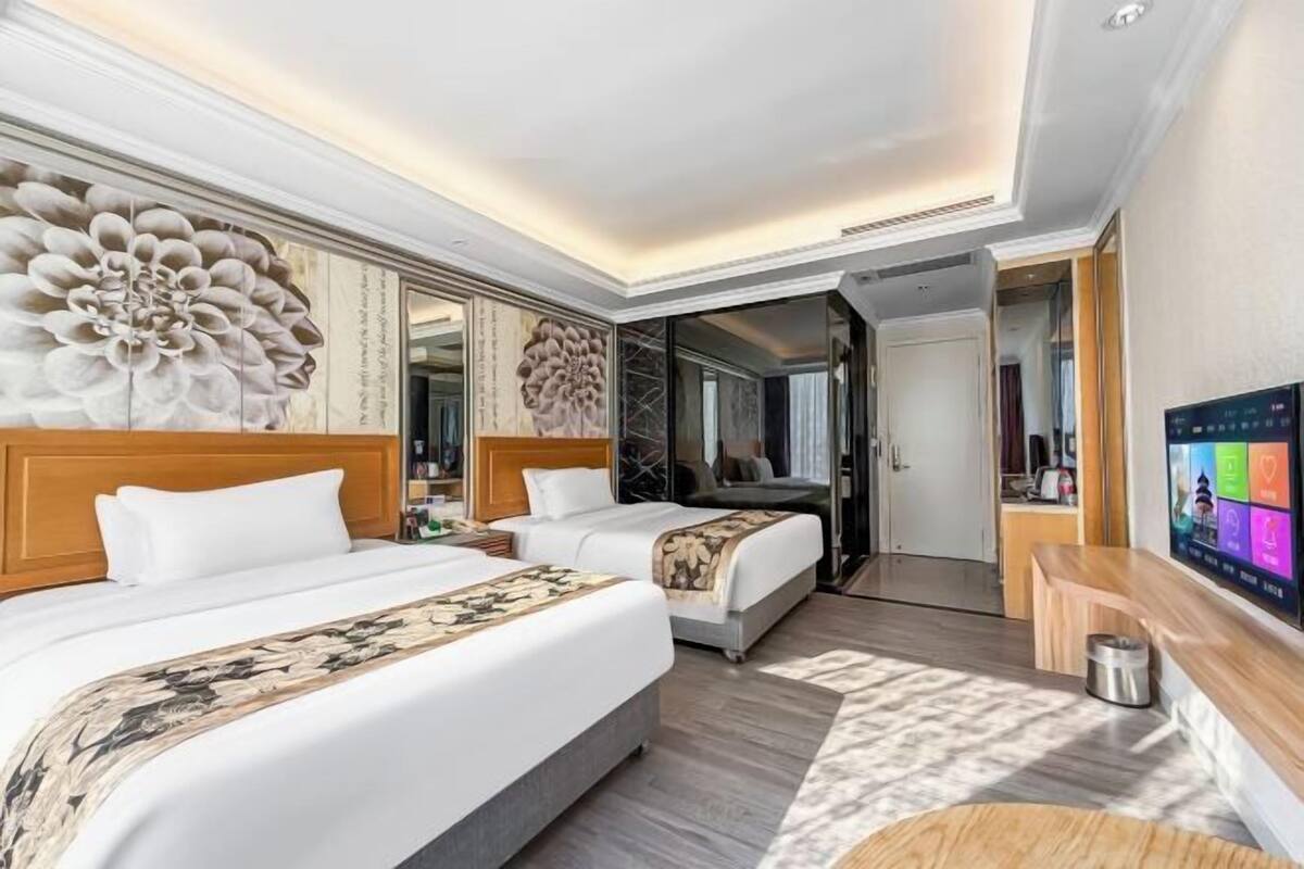 Een hotelkamer met twee bedden, een televisie, een bureau en een spiegel.