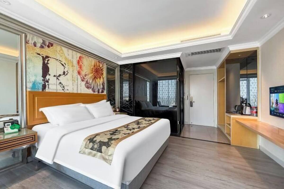 Een moderne hotelkamer met een groot bed, een bureau, een televisie en een deur naar een badkamer.