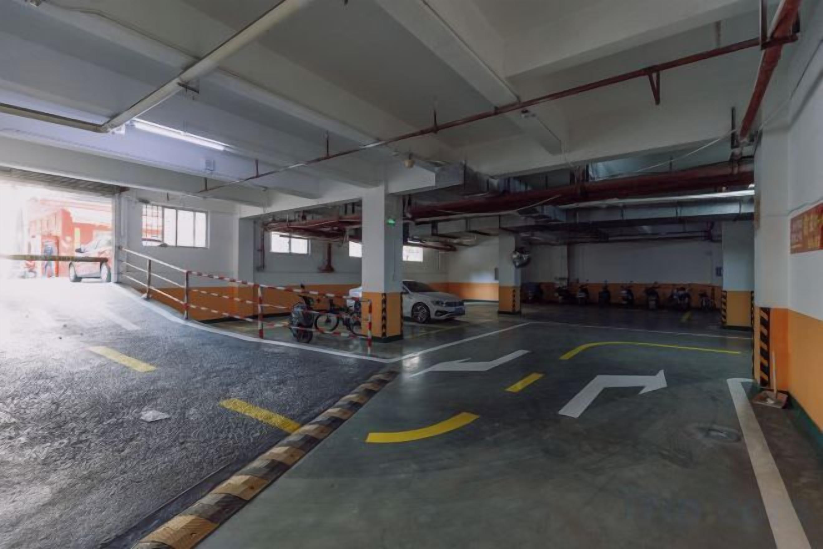 An indoor parking garage with concrete floors, directional arrows, and a white car parked in the distance.