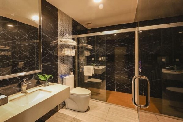 Een moderne badkamer met een glazen douchecabine, een marmeren spatwand en een grote spiegel.