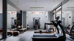 Ein modernes Fitnessstudio mit Laufband, Kraftgeräten und einer Spiegelwand.