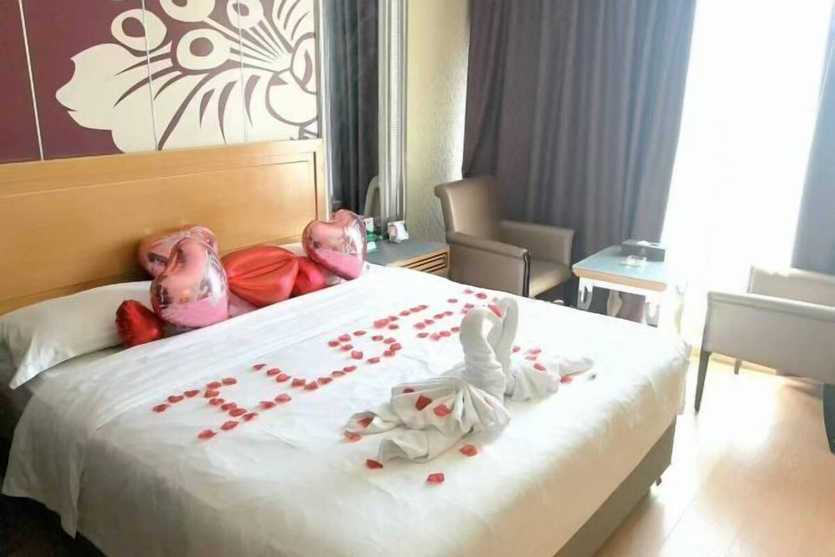 Een hotelkamer met een bed, een stoel, een tafeltje en een raam met gordijnen.