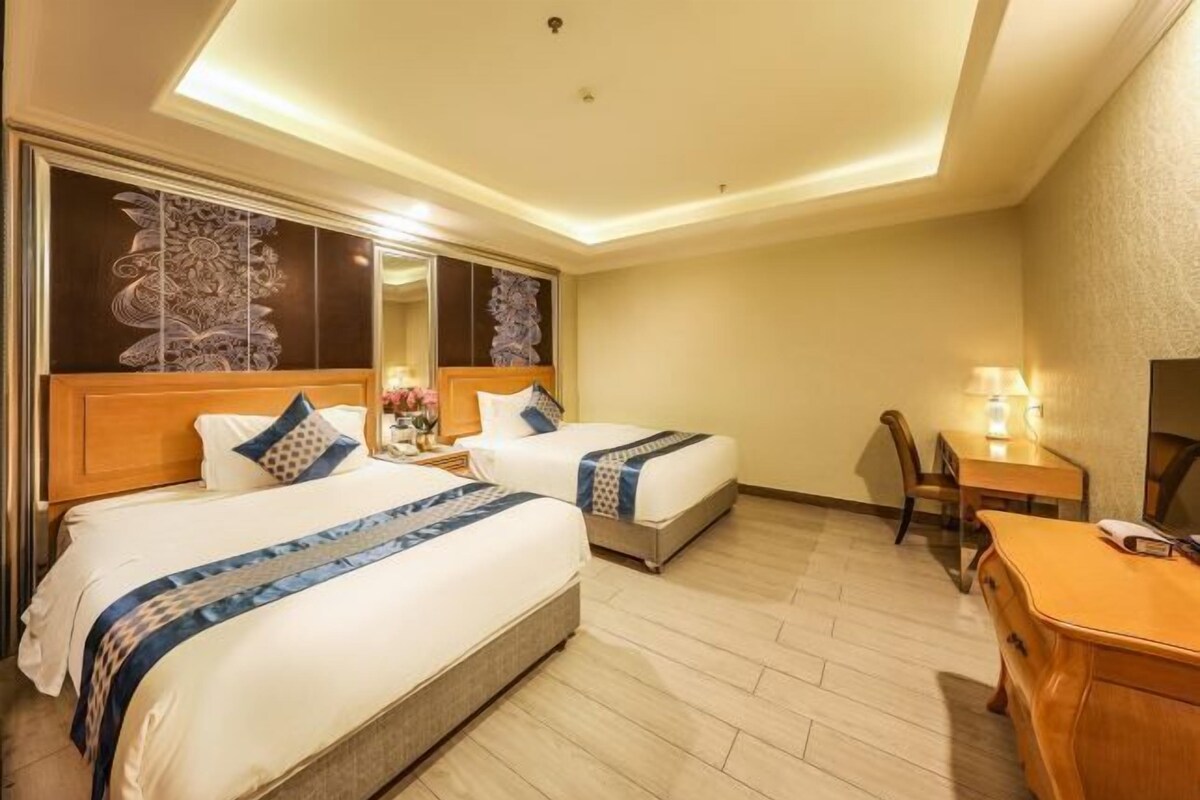 Een hotelkamer met twee bedden, een bureau en een stoel.