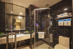 Een moderne badkamer met een douchecabine van glas, een witte wastafel en een toilet.