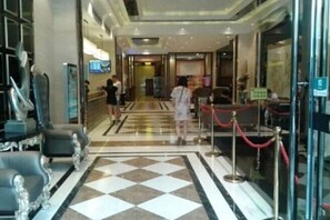 Un vestíbulo de hotel con mostrador de recepción, zona de estar y puerta de cristal de entrada.