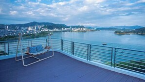 Un balcón con una mecedora que da a un río y vistas de la ciudad.