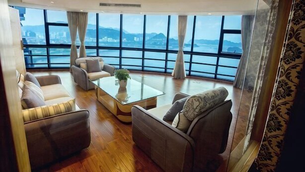 Un amplio salón con un gran ventanal, una mesa de centro y asientos.
