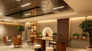 Un área de recepción moderna con un mostrador central, asientos y plantas decorativas.
