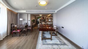 Amplia sala de estar con una mesa de comedor de madera, sillas, una estantería y un tapete estampado.