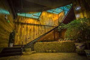 A wooden interior with a staircase, stone wall, and potted plants.