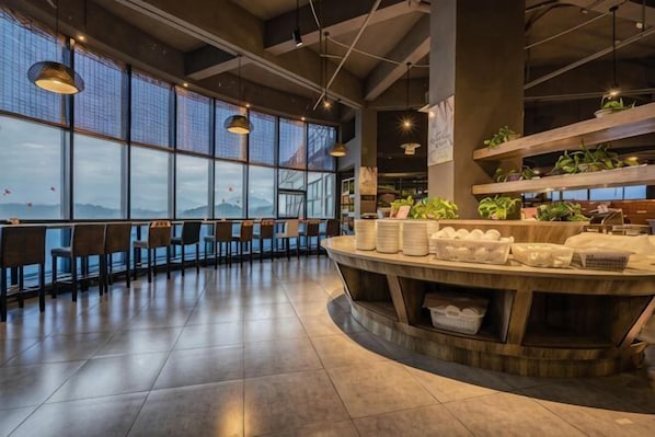 A modern interior with large windows, a curved counter, and seating areas.