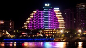 Un hotel con una estructura de varios pisos muy particular, iluminado con luces vibrantes de color morado y azul.