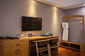 A hotel room with a wooden desk, a television, a robe rack, and a bench. - Yitu Lake View Hotel (Chun'an)
