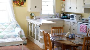 Une cuisine de taille réduite avec des meubles blancs, une table à manger et une fenêtre qui laisse entrer la lumière naturelle.