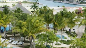 A resort with a pool, palm trees, and a view of the ocean.