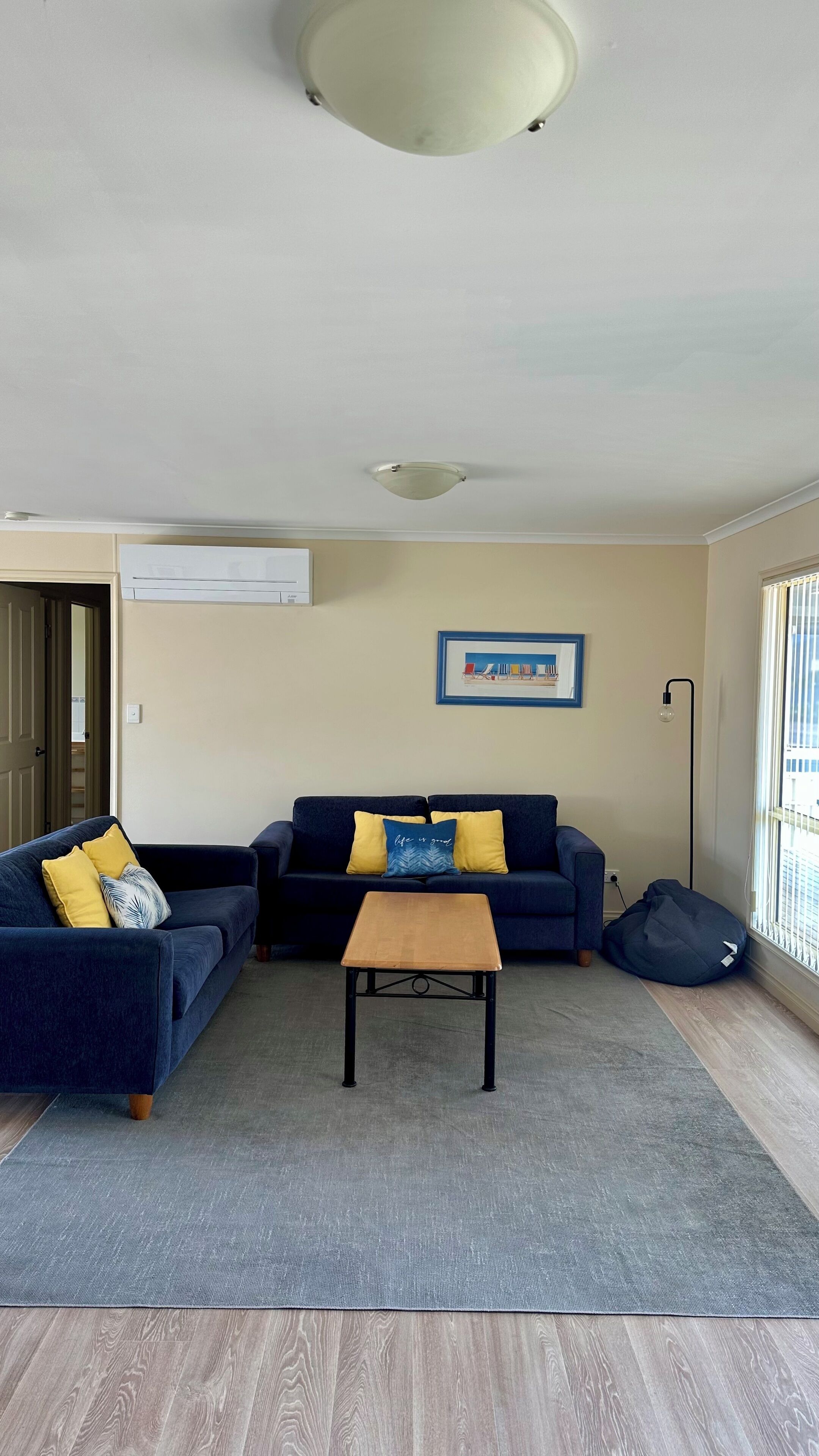 A living room with two dark blue sofas, a wooden coffee table, and a grey rug.