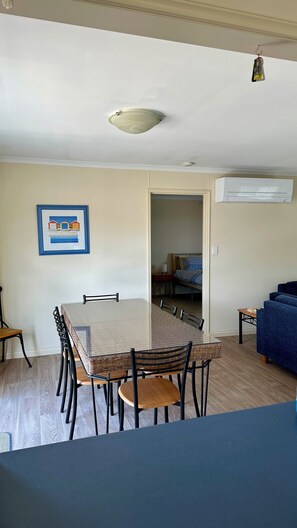 A dining area with a round table and chairs, a blue sofa, and a bed in the background.