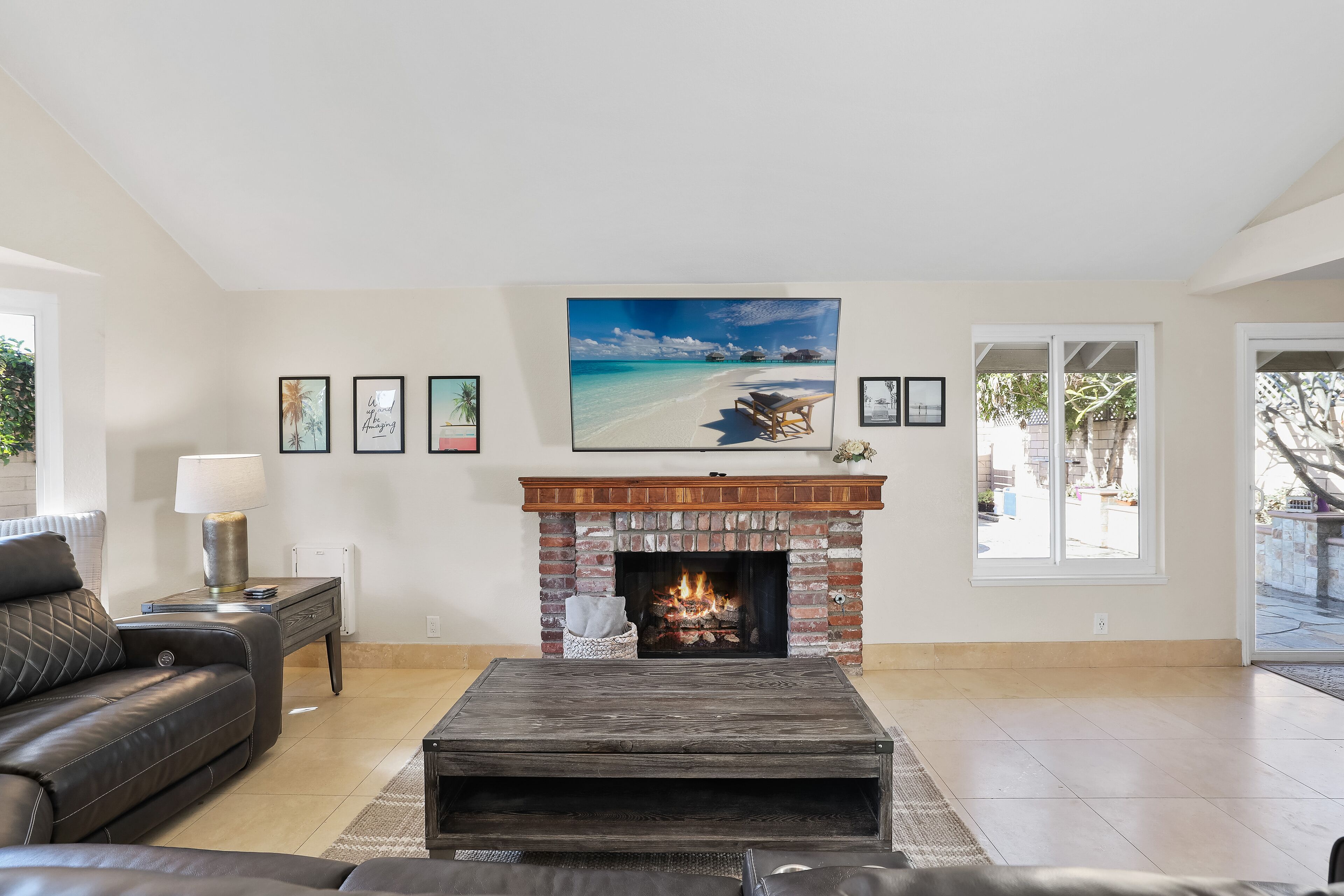 A living room with a fireplace, a sofa, a coffee table, and framed pictures on the wall.