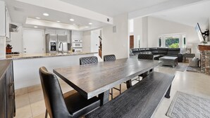 Una cucina moderna con elettrodomestici integrati, un'area pranzo con un tavolo e sedie di grandi dimensioni e un soggiorno con divano e camino.