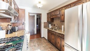 A kitchen with wooden cabinets, a stainless steel refrigerator, and a granite countertop.