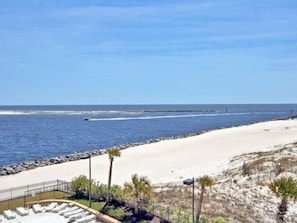 A beach view with a sandy shoreline, a rocky breakwater, and a row of sun loungers.