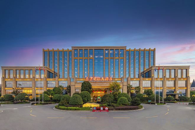 A modern hotel with a symmetrical facade, large windows, and a well-maintained front lawn.