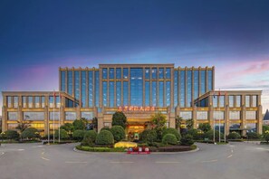Un hôtel moderne à la façade symétrique, doté de grandes fenêtres et d’une pelouse bien entretenue à l’avant.