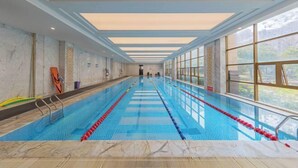 A long indoor swimming pool with clear lanes, large windows, and a view of the outdoors.