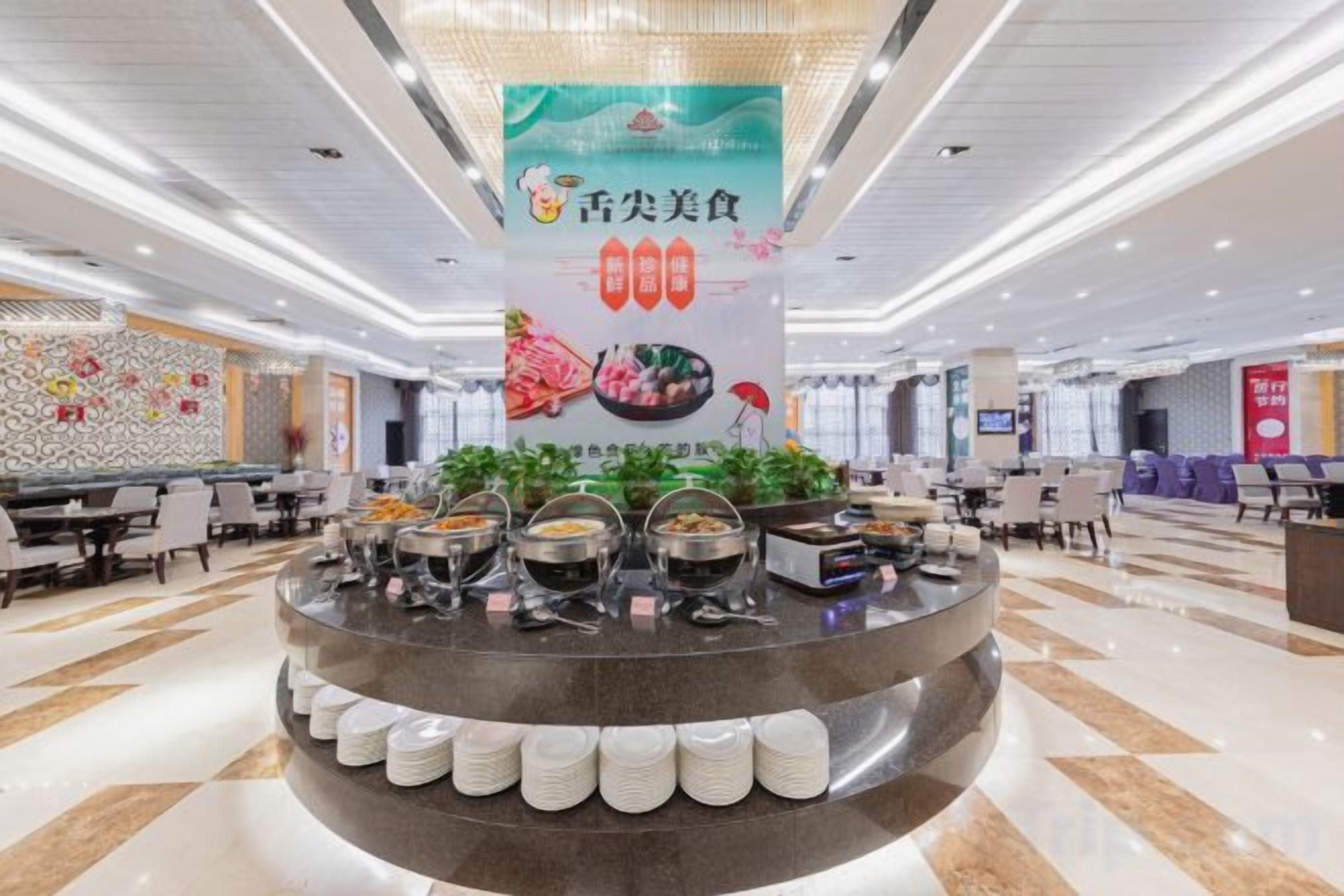 A buffet area with multiple food stations, a central serving counter, and a patterned wall in the background.