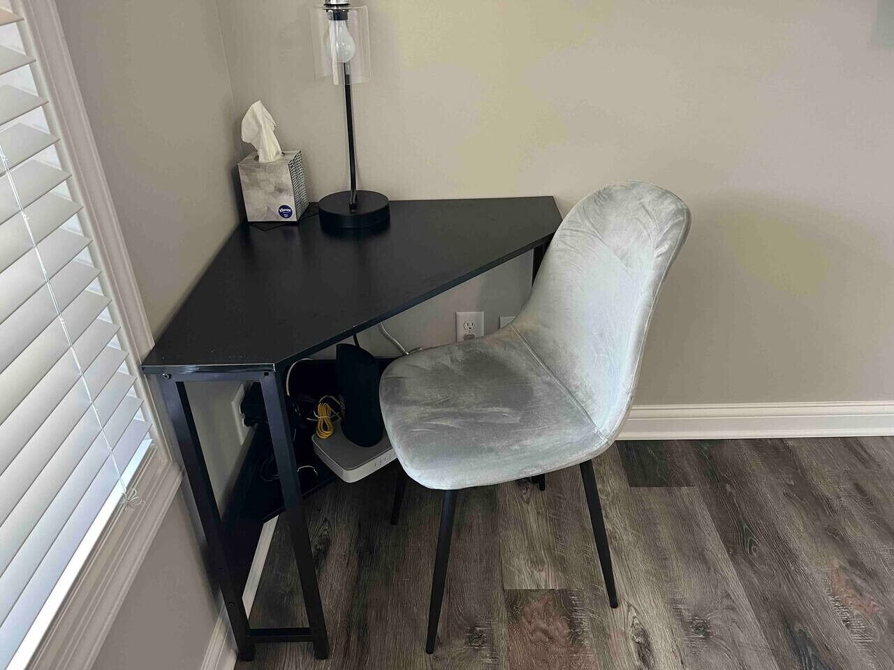 A corner office with a desk, chair, and a lamp.