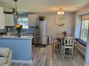 A modern kitchen with a built-in island, stainless steel appliances, and a dining area with a bench and table.