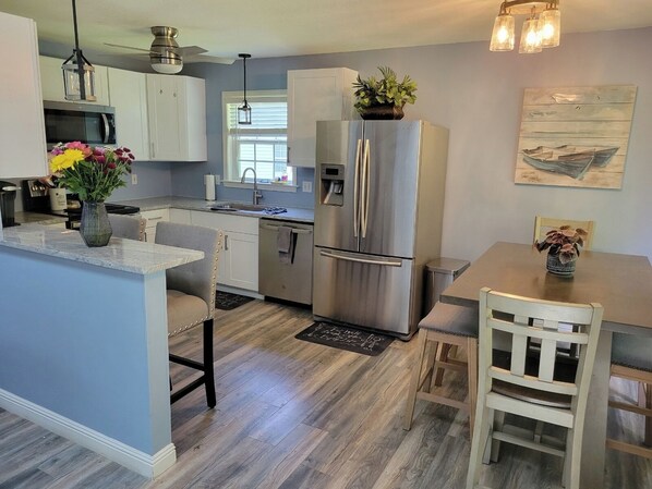 A modern kitchen with a central island, stainless steel appliances, and a dining area with a wooden table and chairs.