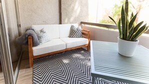 Un balcone con un divano bianco, un tappeto decorato e una pianta in vaso.