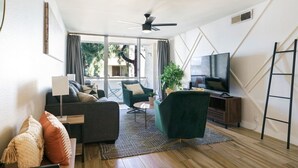 Un soggiorno moderno con divano, poltrona, televisore e ventilatore a soffitto.