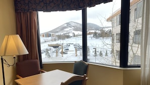 A hotel room with a large window offering a view of a snowy landscape and a mountain. - Lift Base Village - Grand Lodge King Bedroom Suite (Mount Crested Butte)