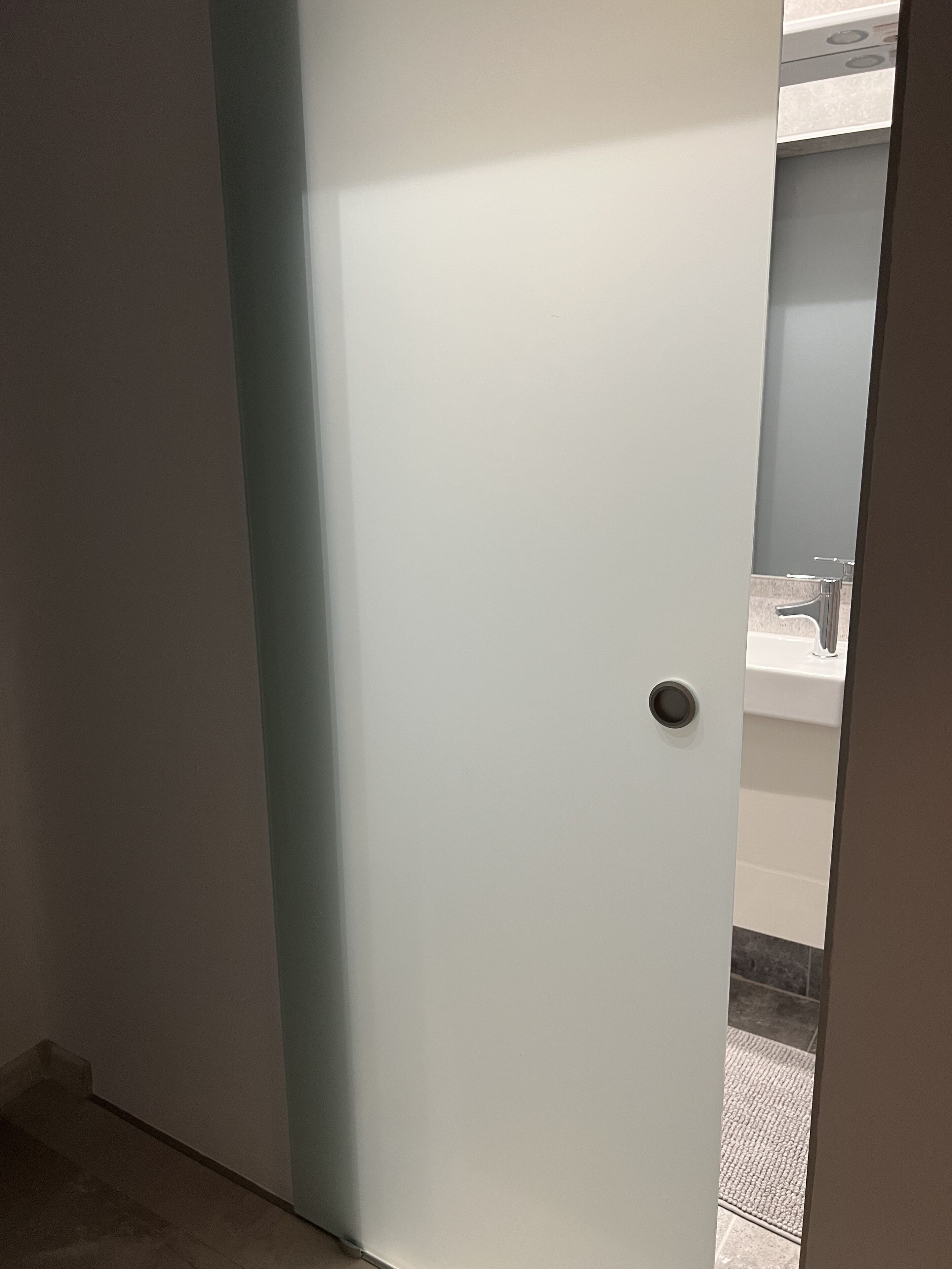 A bathroom with a white door, a sink, and a mirror.