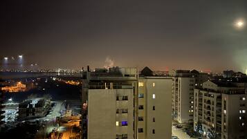 A high-rise building with multiple floors, a parking lot in front, and a cityscape in the background.