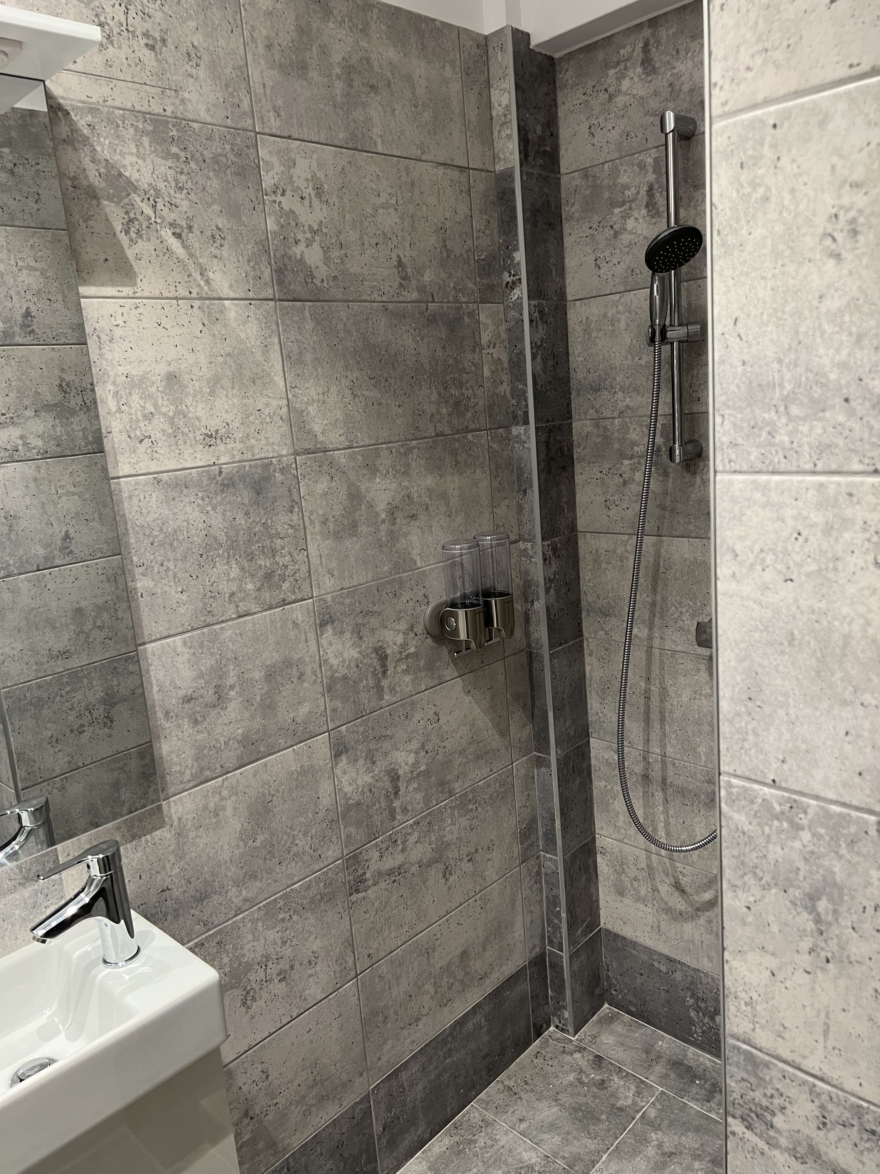 Un baño con ducha, lavamanos y espejo.